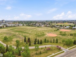 Expansive green space featuring two baseball diamonds, paved walking paths, a variety of mature trees, and landscaping - 