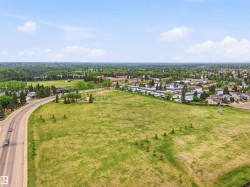 Expansive green field bordered by a paved road and residential structures - 
