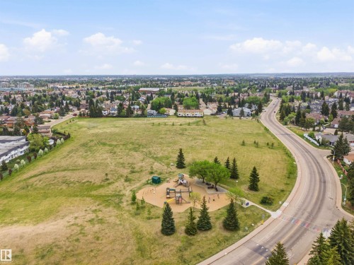 Expansive green space featuring a playground with multiple structures, mature evergreen and deciduous trees, and paved pedestrian paths - 2005 Saddleback Road, Edmonton, AB - Outdoor With View