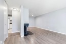 Spacious living area featuring wood-finish flooring, light gray walls, a built-in fireplace with a dark tile hearth, and overhead lighting - 2005 Saddleback Road, Edmonton, AB  - Indoor Photo Showing Other Room 
