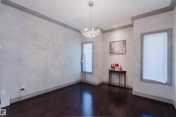 Neutral-toned interior room featuring rich dark wood-finish flooring, substantial baseboards, and elegant crown molding - 