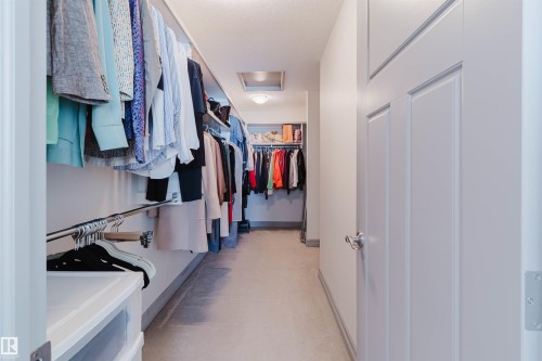 Dedicated walk-in closet featuring built-in shelving, multiple hanging rods, recessed lighting, and light-toned carpeting - 4377 Mcclung Crescent, Edmonton, AB 