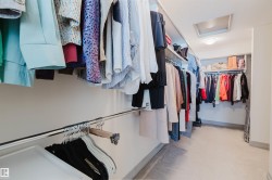 Spacious walk-in closet featuring multiple shelving units, chrome hanging rods, recessed lighting, and light-colored flooring - 