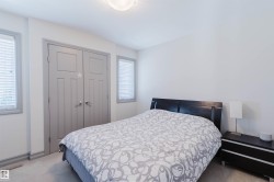 Bedroom featuring light gray walls, plush carpeting, two windows with blinds, a ceiling-mounted light fixture, and a built-in double-door closet with gray paneled doors - 