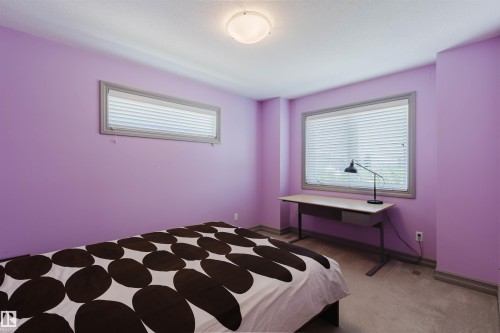 Room with lavender-toned walls, featuring a single flush-mount ceiling light fixture, two windows with horizontal blinds, and grey-toned trim - 4377 Mcclung Crescent, Edmonton, AB 