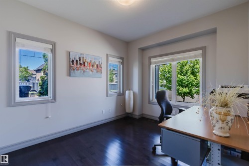 Bright room featuring dark wood-finish flooring and multiple windows with grey trim - 4377 Mcclung Crescent, Edmonton, AB 