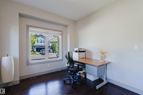 Spacious room featuring dark wood-finish flooring, light-colored walls, and a large window with roller shades - 4377 Mcclung Crescent, Edmonton, AB 