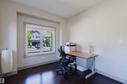 Spacious room featuring dark wood-finish flooring, light-colored walls, and a large window with roller shades - 