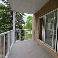 Private balcony featuring a textured floor, white metal railings, and a stucco exterior wall - 