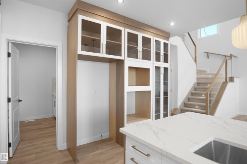 Integrated custom cabinetry featuring wood-finish framing and glass-front upper cabinets - 6403 29 Ave, Edmonton, AB - Indoor
