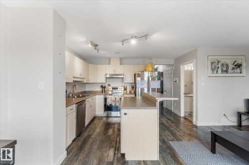 Kitchen featuring cream cabinetry, stainless steel appliances, a kitchen island with seating, dark wood-finish flooring, and recessed lighting - 2324 30 Avenue, Edmonton, AB 