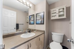 Bathroom featuring an integrated sink, vanity with under-sink storage, full wall mirror, and a wall-mounted light fixture - 