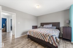 Spacious bedroom featuring wood-finish flooring, light grey painted walls, and a light-colored ceiling - 
