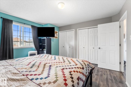 Bedroom featuring a large window, wood-finish flooring, and multiple closet doors - 2324 30 Avenue, Edmonton, AB 