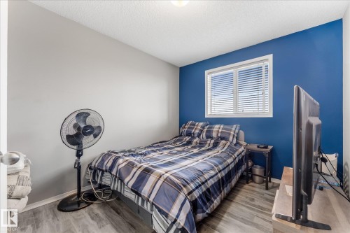 Bedroom featuring light wood-finish flooring, a bright window with horizontal blinds, and a contrasting accent wall - 2324 30 Avenue, Edmonton, AB 