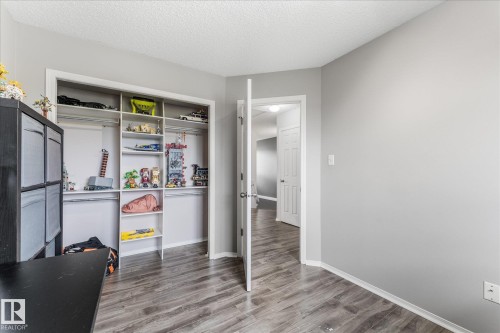 Neutral gray walls with white trim, wood-finish flooring, and a built-in closet organization system featuring shelving and hanging rods - 2324 30 Avenue, Edmonton, AB 