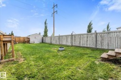 Spacious grass yard featuring a wooden privacy fence, a storage shed, and a circular fire pit - 