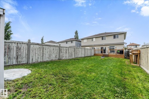 Expansive backyard featuring a wood deck, green lawn, full perimeter fencing, and a concrete pad - 2324 30 Avenue, Edmonton, AB 