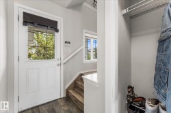 Entryway featuring a white door with a window, wood-finish flooring, and a built-in closet with shelving - 