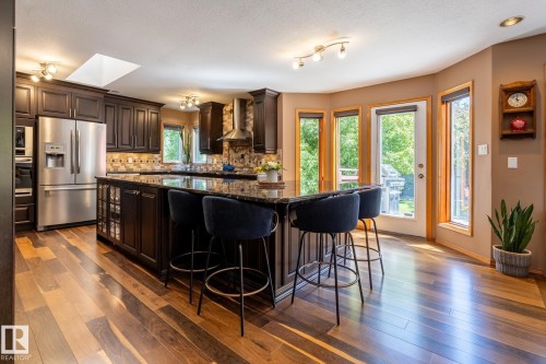 Spacious kitchen featuring rich wood-finish flooring, dark cabinetry, and a substantial island with a dark countertop - 315 Osland Place, Edmonton, AB 