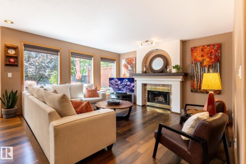 Living room with wood-finish flooring, a fireplace featuring a white mantel and arched alcove, and recessed lighting - 315 Osland Place, Edmonton, AB 