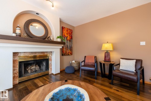 Living space featuring a prominent fireplace with a brass-trimmed firebox and a stone surround - 315 Osland Place, Edmonton, AB 