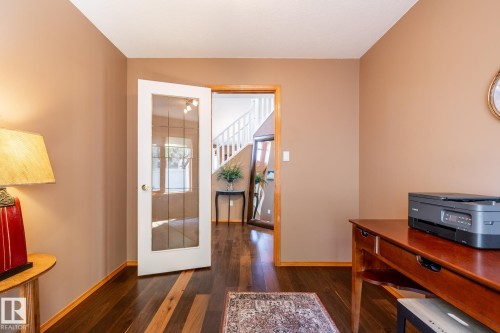 Room featuring wood-finish flooring, warm-toned walls, and a glass-paneled interior door - 315 Osland Place, Edmonton, AB 