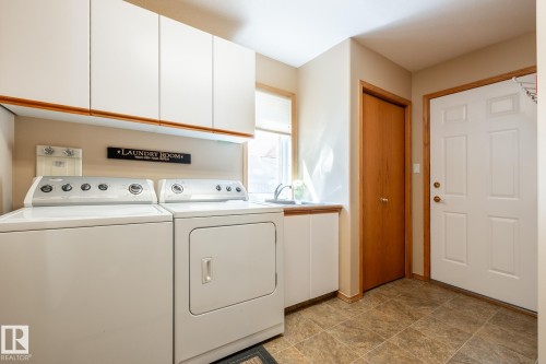 Laundry area featuring white cabinetry, a utility sink, and tile flooring - 315 Osland Place, Edmonton, AB 