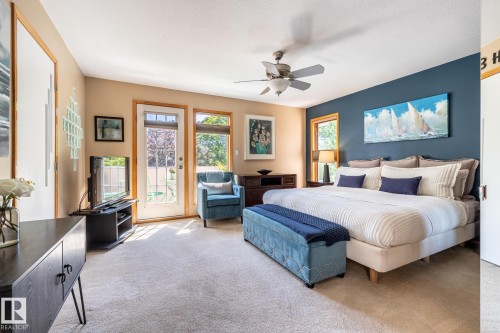 Spacious room with a neutral carpet flooring, featuring a ceiling fan and a blue accent wall - 315 Osland Place, Edmonton, AB 