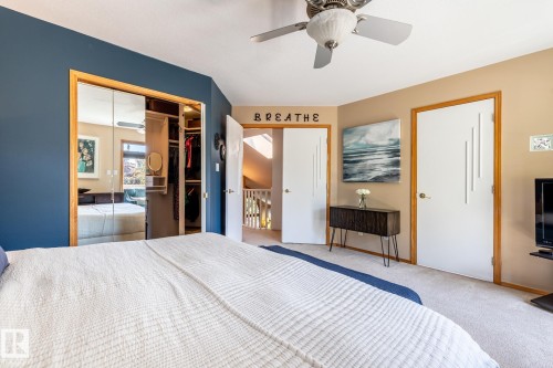 Bedroom featuring a ceiling fan, mirrored closet doors, custom closet organization system, two panel doors with modern detailing, and carpet flooring - 315 Osland Place, Edmonton, AB 