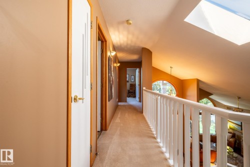 Upper-level hallway featuring a skylight, light tan wall color, and a white baluster railing overlooking the lower level - 315 Osland Place, Edmonton, AB 