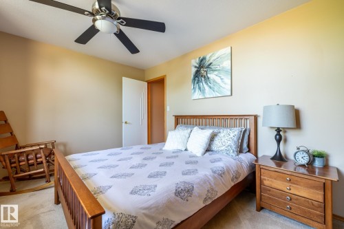 Bedroom featuring a ceiling fan with integrated lighting, a light-colored wall finish, and a door with a white finish - 315 Osland Place, Edmonton, AB 