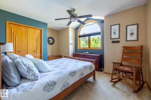 Bedroom with textured carpeting, a wood-finish bed frame, and a ceiling fan with integrated lighting - 315 Osland Place, Edmonton, AB 