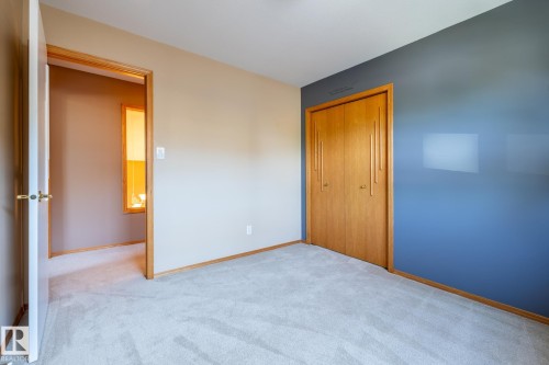 Carpeted room featuring a light wood bi-fold closet, a vibrant blue accent wall, and neutral painted walls - 315 Osland Place, Edmonton, AB 