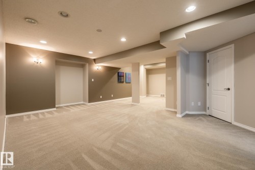 Spacious room featuring neutral carpeting, recessed lighting, wall sconces, two-tone painted walls, and white trim molding - 315 Osland Place, Edmonton, AB 