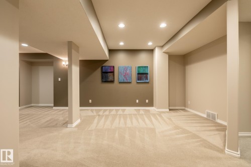 Spacious carpeted room featuring recessed lighting, a neutral color palette, architectural columns, and baseboard trim - 315 Osland Place, Edmonton, AB 