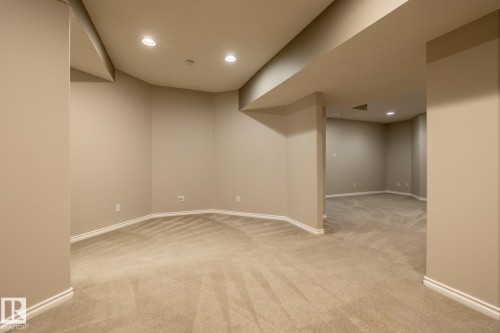 Expansive carpeted area with recessed lighting, neutral wall tones, white baseboards, and multiple distinct sections - 315 Osland Place, Edmonton, AB 