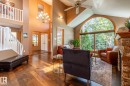 Living area featuring an arched picture window, wood-finish flooring, a stone-clad fireplace, and a vaulted ceiling with a fan - 315 Osland Place, Edmonton, AB 