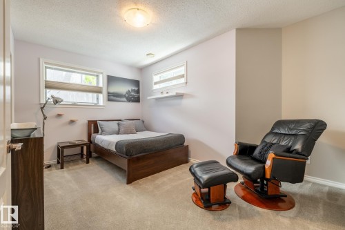 Carpeted room with a ceiling-mounted light fixture, two windows with blinds, and white baseboards - 315 Osland Place, Edmonton, AB 