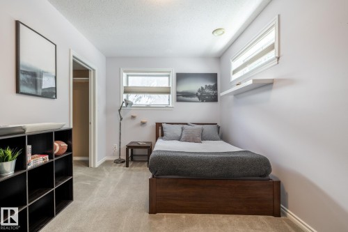 Carpeted room featuring a dark wood-finish bed frame, built-in shelving unit, and a window with a blind - 315 Osland Place, Edmonton, AB 