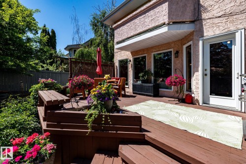 Multi-level wood deck featuring a textured stucco exterior, multiple large windows, and a glass-paneled door - 315 Osland Place, Edmonton, AB 