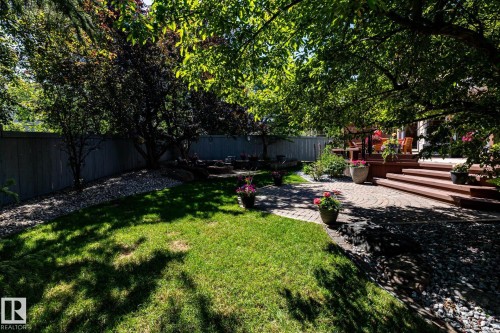 Expansive backyard featuring a multi-level wood deck, paver patio, lush lawn, and mature trees - 315 Osland Place, Edmonton, AB 