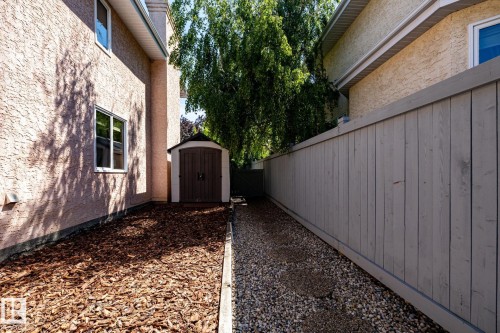 Compact exterior storage shed with double doors, set on a wood chip landscape feature - 315 Osland Place, Edmonton, AB 