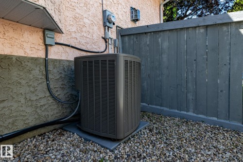 Outdoor A/C unit on a gravel base, positioned against a textured stucco exterior - 315 Osland Place, Edmonton, AB 