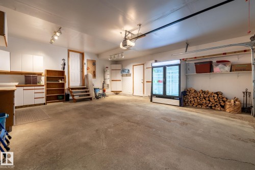 Spacious garage featuring a concrete floor, built-in cabinetry, overhead track lighting, and interior access doors - 315 Osland Place, Edmonton, AB 