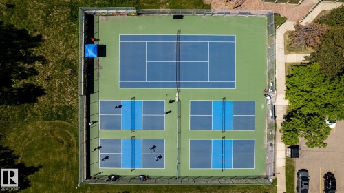 Fenced recreation area featuring a full-size tennis court and four pickleball courts with painted lines - 315 Osland Place, Edmonton, AB 