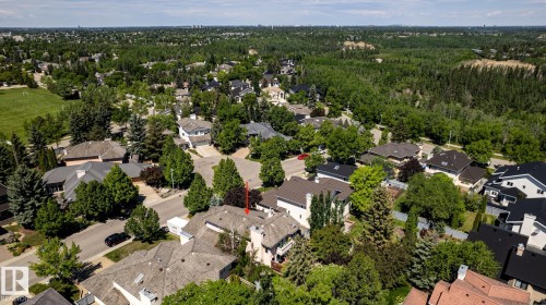Residential property featuring a grey shingle roof, chimney, and mature surrounding trees, located within a developed community with extensive green spaces and distant tree lines - 315 Osland Place, Edmonton, AB 