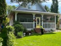 Exterior featuring a screened-in porch with decorative white railings, a bright yellow entry door, and a dormer window - B13 Johnsonia Beach, Rural Leduc County, AB 