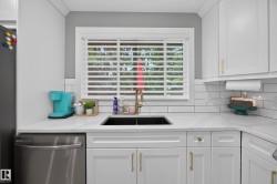 Kitchen featuring white shaker-style cabinetry with gold-toned hardware, solid surface countertops, and a white subway tile backsplash - 