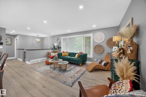Open-concept living space featuring light wood-finish flooring, recessed ceiling lighting, and a prominent window with white blinds - 43 Burnham Place, St. Albert, AB 